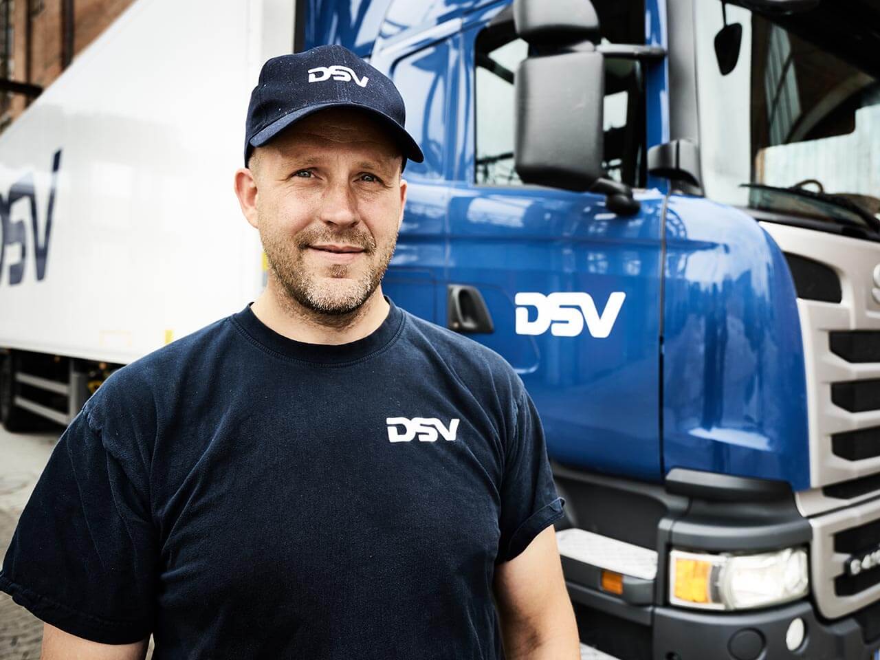 Chaufför som står framför DSV lastbil
